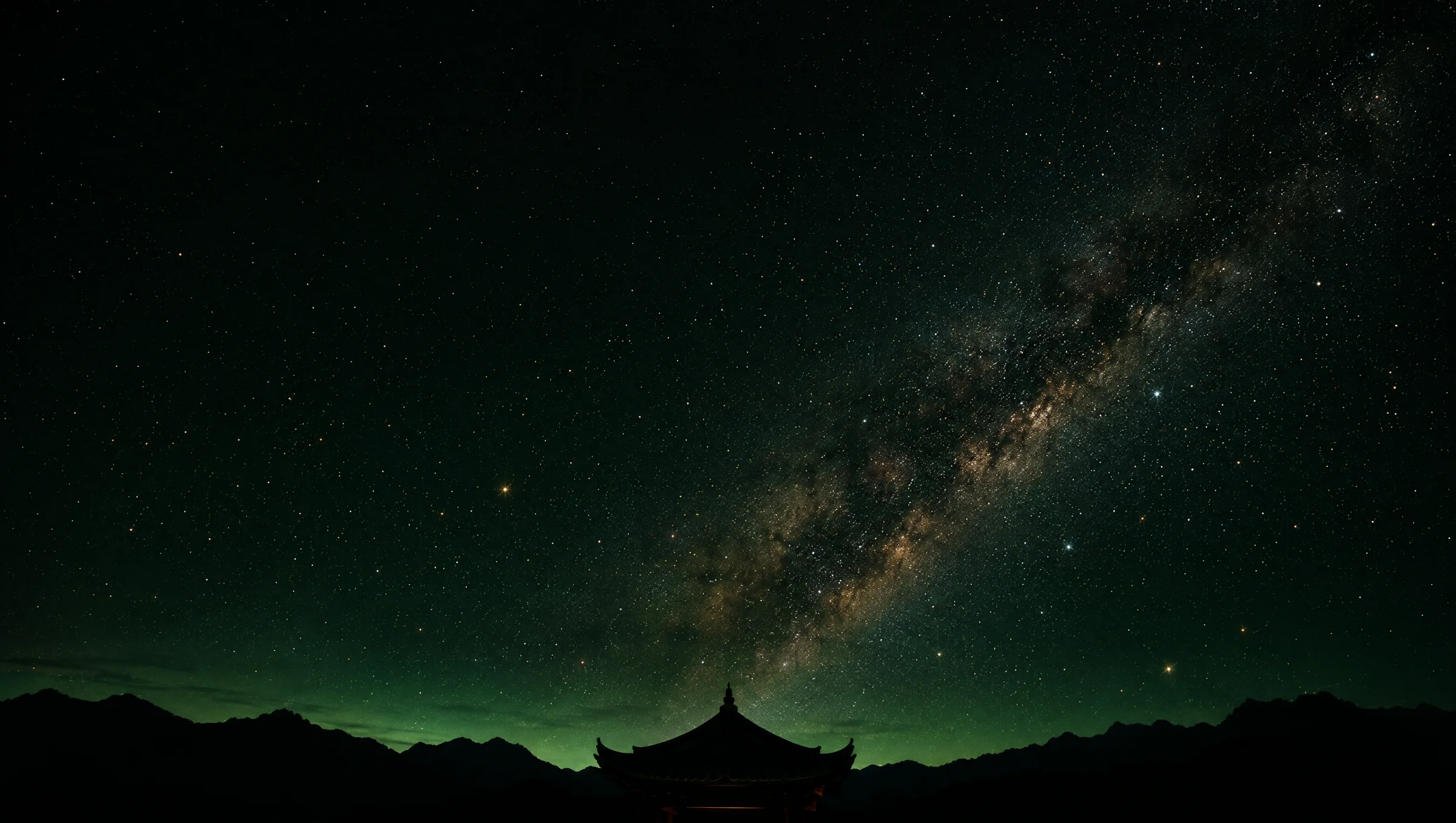 The Milky Way over a mountain ridge and a temple roofline